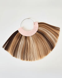 Hair color swatch ring displaying multiple shades of brown and blonde for selecting hair extension colors.