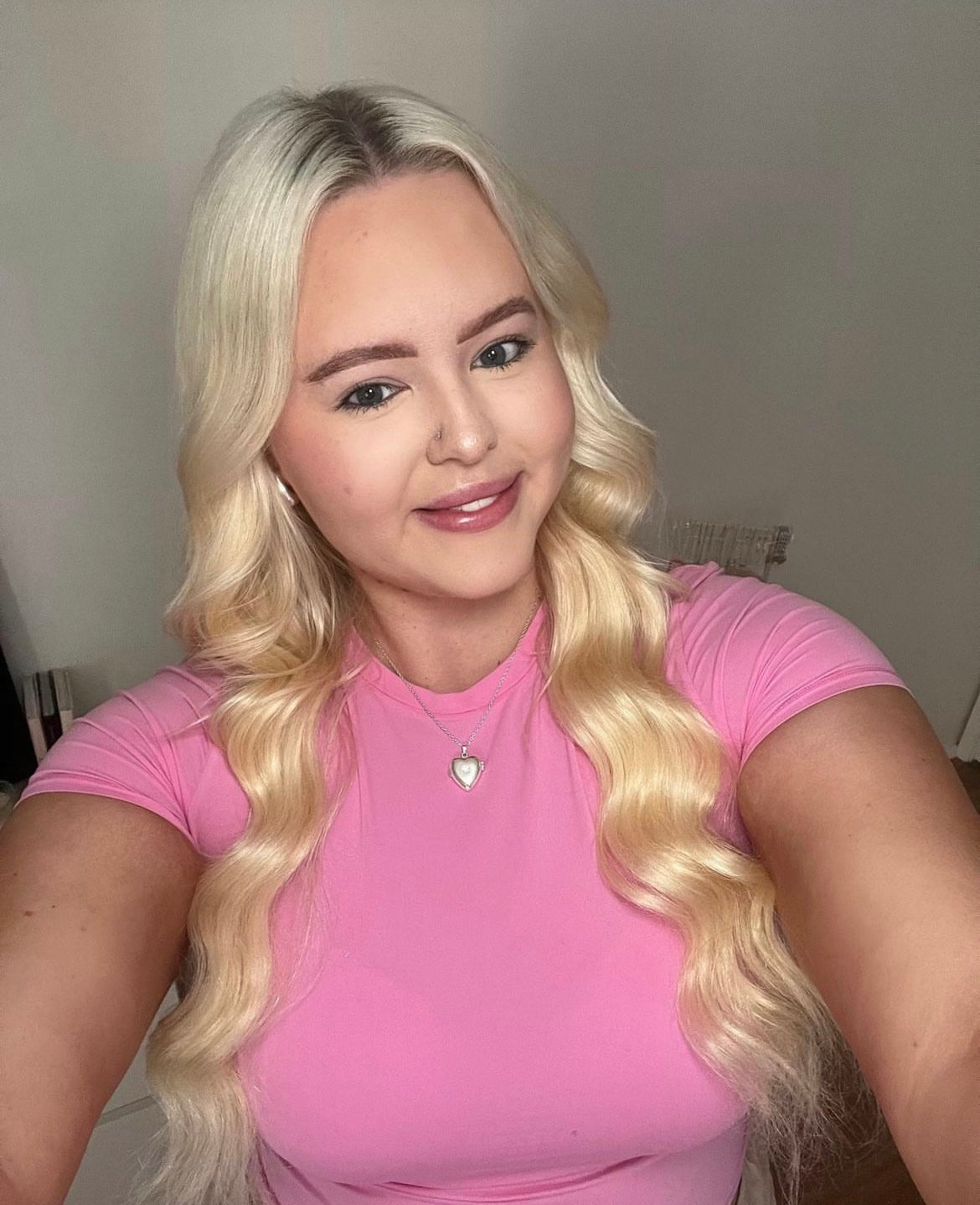 Smiling woman with long wavy blonde hair wearing a pink top showcasing Buttercream Blonde 