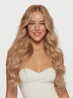 Young woman with long wavy hair wearing a white top showcasing Strawberry Blonde 